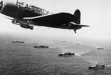Convoy of ships crossing guarded by a plane