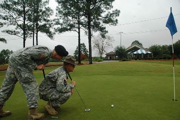 Two soldiers playing golf about to putt
