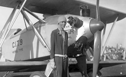 Amelia Earhart standing by her airplane
