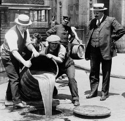 Men pouring bear into a drain