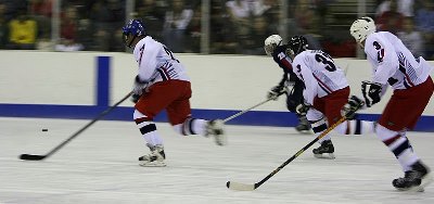 Hockey players skating fast towards puck